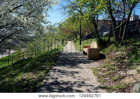 One may sit on a bench and enjoy the view of downtown Joliet, Illinois, and of the riverfront, from the top of the bluff above Billie Limacher Bicentennial Park.