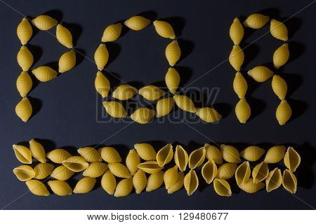 English alphabet laid out in the form of pasta shells on a dark background .