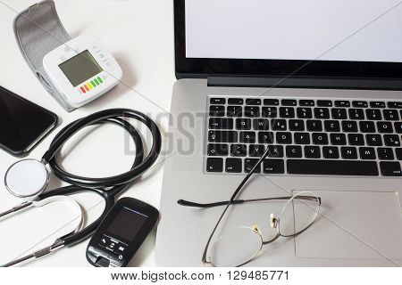 close up of doctor's desk with Laptop Stethiscope and other devices
