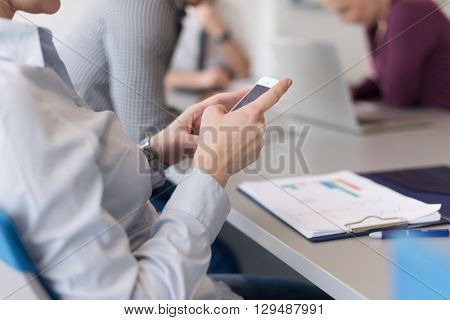 close up of  businesswoman hands  using smart phone, people group in office meeting  room blurred in backgronud