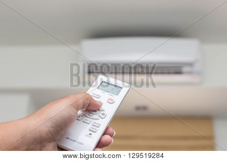 Hand Holding Remote Control Directed On The Conditioner