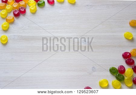 Colorful candy decoration frame over wooden white background