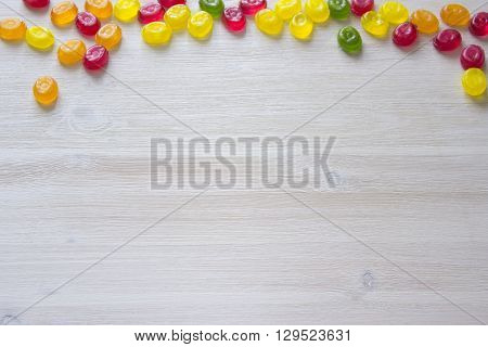 Colorful candy decoration frame over wooden white background