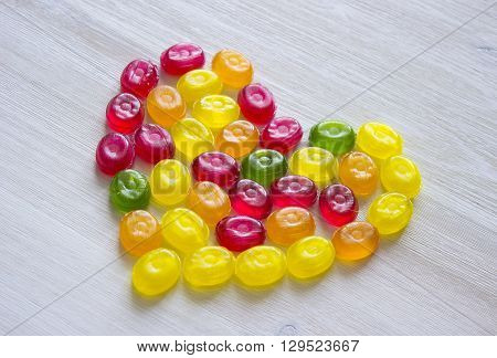 heart symbol made of sweet candy isolated on white wooden background