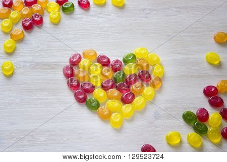 heart symbol made of sweet candy isolated on white wooden background