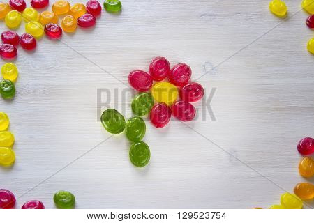 flower made of sweet candy isolated on white wooden background