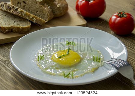 Breakfast: Fried egg in form of a clock, tomato and bread with fork