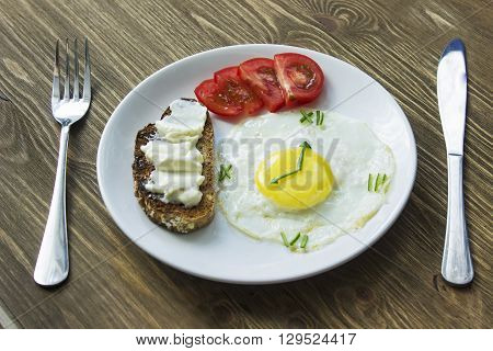 Breakfast: Fried egg in form of a clock, tomato and sandwich with fork and knife