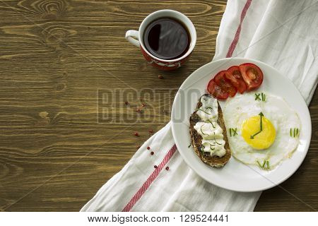 Breakfast: Fried egg in form of a clock, tomato, sandwich and coffee