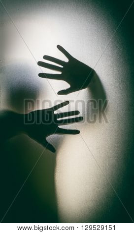Shadowy figure behind glass. 
Dramatic film grain