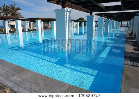 HERAKLION, CRETE, GREEC, - MAY 13 2014: The blue swimming-pool modern building with columns and beach in popular luxury class hotel on the Mediterranean coast of Crete, May 13, 2014, Greece.