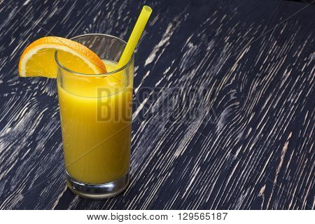 Orange juice in the glass on black wooden table