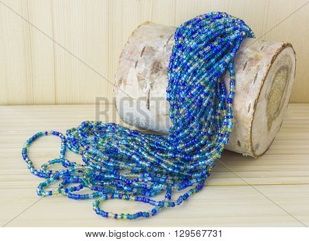 Multicolor beads necklace on birch log. Rustic style background