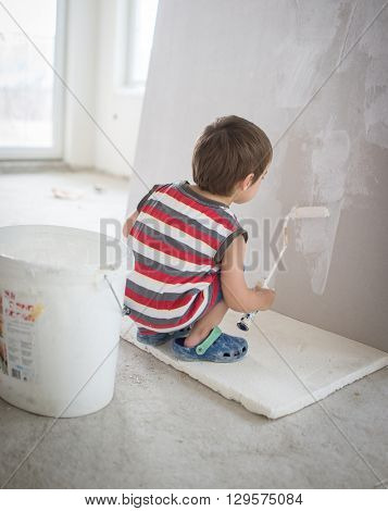 Little cute boy painting on a wall