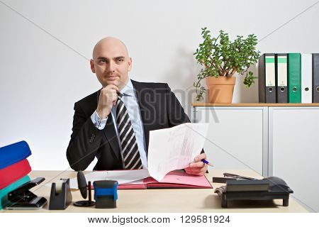 Manager checks an offer. He sits in his office.