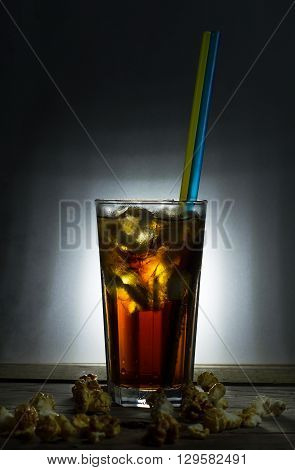 Glass of cola with ice on old wooden table