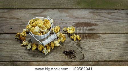 White bucket with popcorn on wooden background