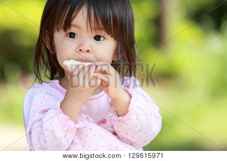 Japanese girl eating rice cracker (1 year old)