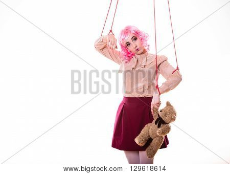 Mental disorder concept. Young woman girl stylized like marionette puppet on string with teddy bear toy isolated on white background