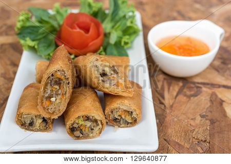 Closeup photo of egg rolls in Thai style with sweet sauce on wooden table spring rolls or popiah
