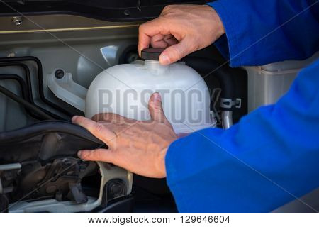 Close-up of mechanic checking a coolant water tank at the repair garage
