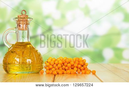 Bunch of sea buckthorn and oil bottle closeup on a green background