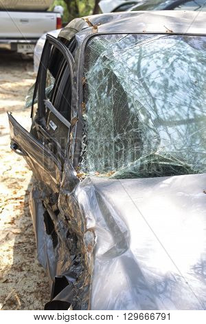 A wrecked car lays in wait after a vicious car accident. Rescue workers linger in the background.