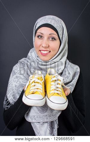 Beautiful muslim woman holding a yellow sneakers