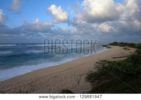 Waves break and crash towards the Hanakailio Beach with dramatic blue-pink cloudy skyline at dusk on the North Shore of Oahu Hawaii.