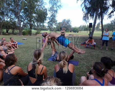 NORTH SHORE HAWAII - FEBRUARY 26: AcroYoga Teacher Jason Nemer balances instructor as class watches demonstration at Wanderlust yoga event on the North Shore Hawaii on February 26 2016.