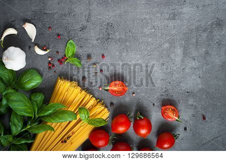 Ingredients for cooking Italian pasta - spaghetti tomatoes basil and garlic. Top view with space for taxt.