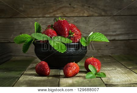 Strawberries in a clay bowl on a wooden background