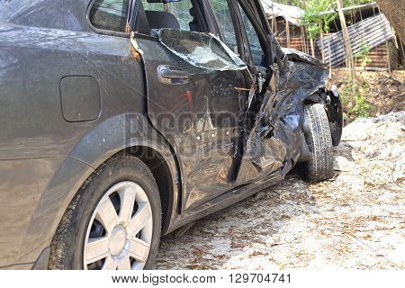 A wrecked car lays in wait after a vicious car accident. Rescue workers linger in the background.