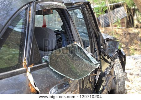A wrecked car lays in wait after a vicious car accident. Rescue workers linger in the background.