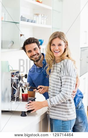 Portrait of young couple preparing coffee from coffeemaker at home