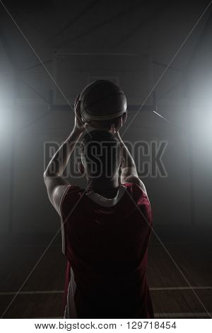 Portrait of basketball player front the back preparing to score on a gym