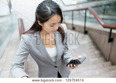 Business woamn use of cellphone and going up the staircase