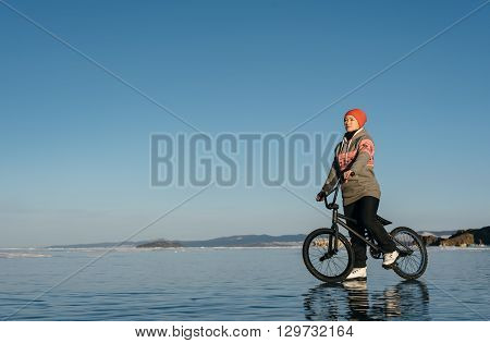 Girl standing on a bmx on the beautiful and dangerous ice.