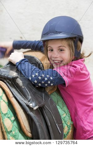 pretty young teenage girl preparing taking care horse poney