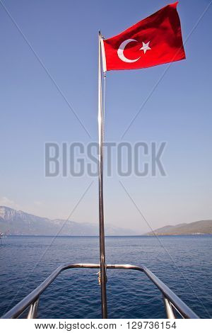 Turkish flag on a ship mast with sea background.