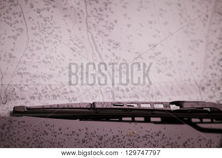 Color image of the wipers of a car with rain drops on the windshield.