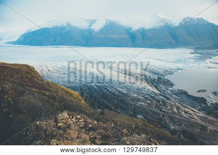 Melting of glacier in Iceland. Panorama of glacial Vatnajokull covered with volcanic ash.