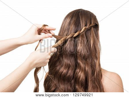 Hands hairdresser braided lock of the girl with long hair isolated on white yone.