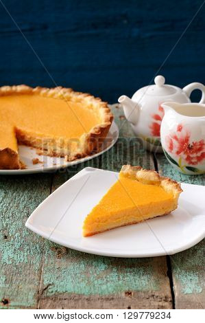 Homemade yummy pumpkin pie and teaware on old table painted blue vertical