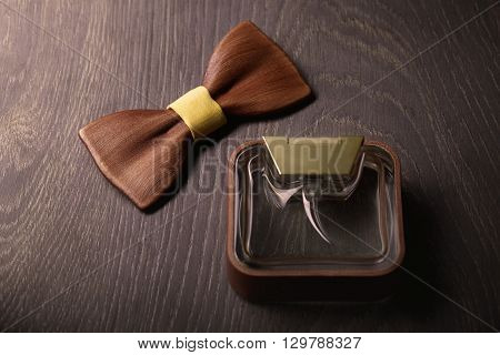 Bottle of male perfume and wooden bow tie on the wood background. Success story concept.