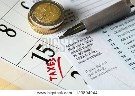 A red tax mark in the calendar, euro coins and tax form, close up