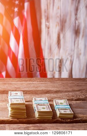 American flag and dollar bundles. Bundles of cash beside flag. Capital is growing. Earn and multiply.