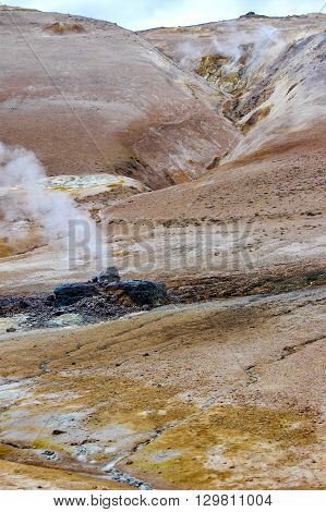 Steam escapes from an active volcano with red earth and sulphur.