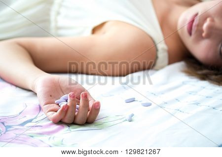 Woman's hand lying on the bed with suicide pills. Conceptual of Suicide and sadness.