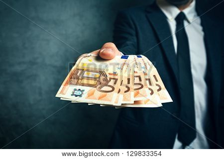 Businessman from bank offering money loan in euro banknotes selective focus.